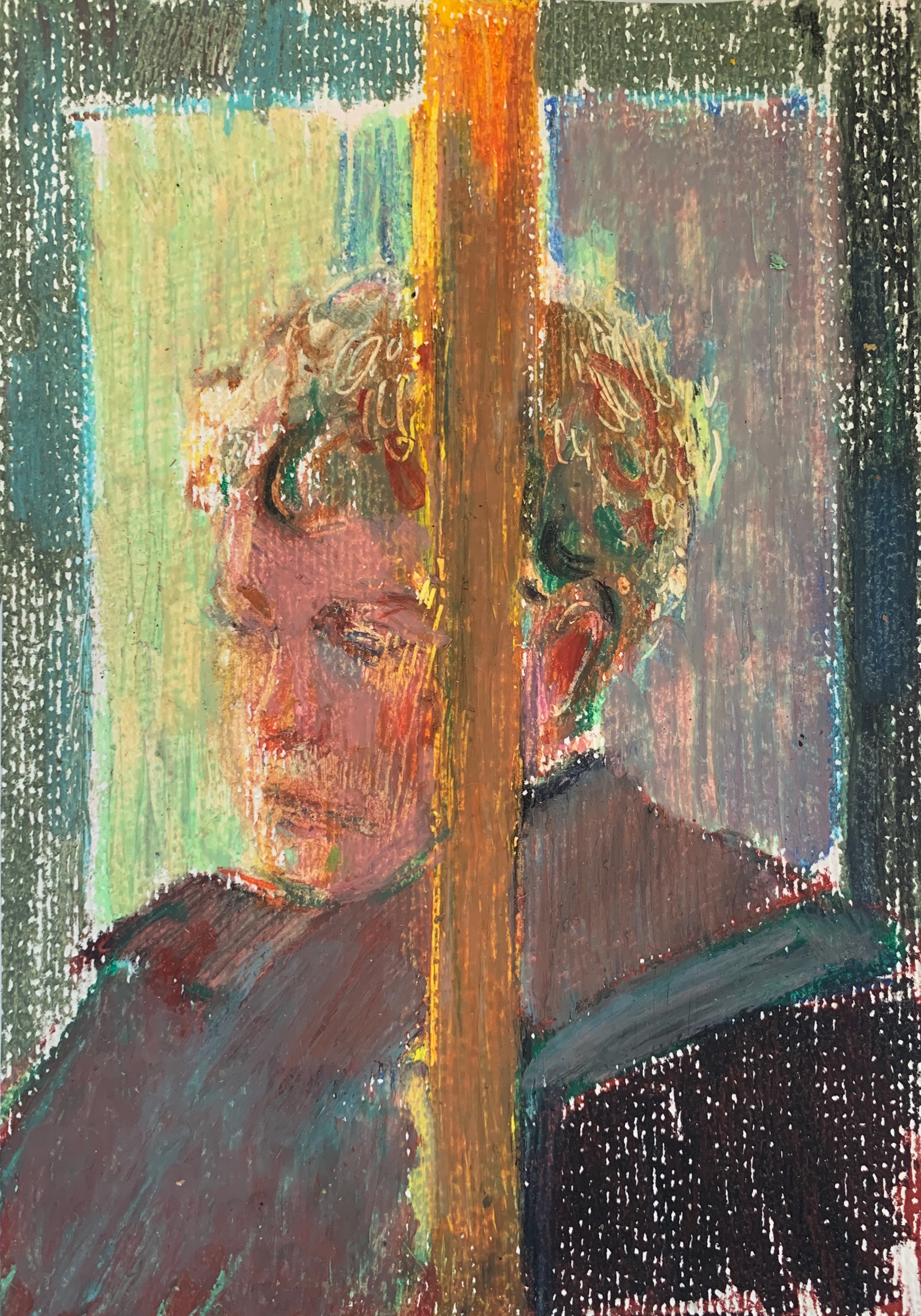 A man looking to the side with his face partially hidden behind a vertical pole.